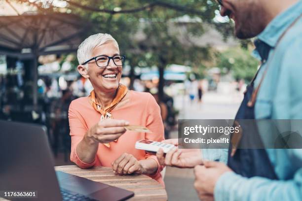 femme aîné payant avec une carte de crédit - customer satisfaction photos et images de collection