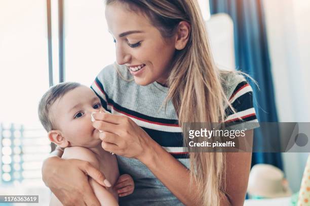 mother cleaning baby's runny nose - rubbing stock pictures, royalty-free photos & images