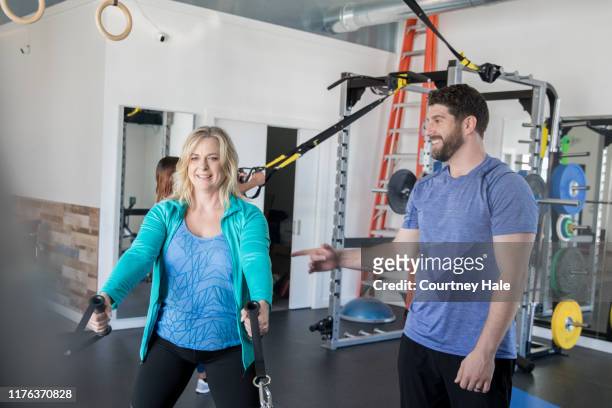fitnesstrainer hilft reife erwachsene frau - sportmedizin happy stock-fotos und bilder
