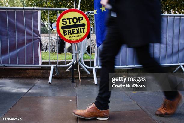 Man walks past a 'Stop Brexit' placard fixed to railings on Abingdon Street outside the Houses of Parliament in London, England, on October 17, 2019....