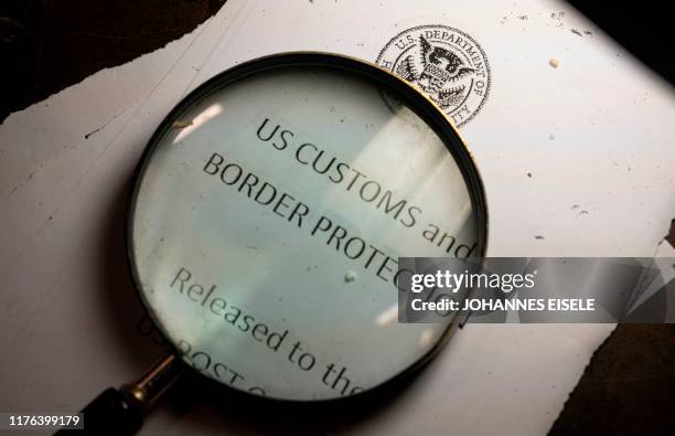 Magnifying glass is seen next to a logo of the Customs and Border Protection, Trade and Cargo Division at John F. Kennedy Airport's US Postal Service...