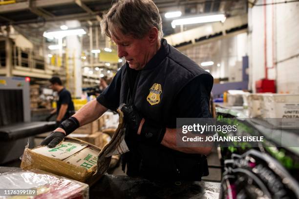 An officer from the US Customs and Border Protection, Trade and Cargo Division finds Oxycodone pills in a parcel at John F. Kennedy Airport's US...