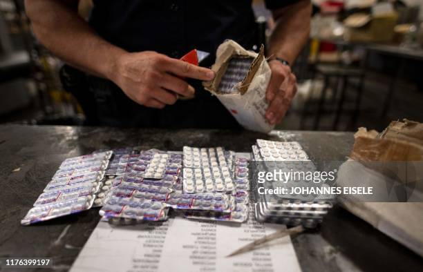 An officer from the US Customs and Border Protection, Trade and Cargo Division finds Oxycodone pills in a parcel at John F. Kennedy Airport's US...