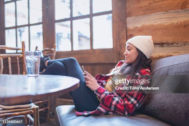 young woman with phone inside cabin in winter - red sofa stock pictures, royalty-free photos & images