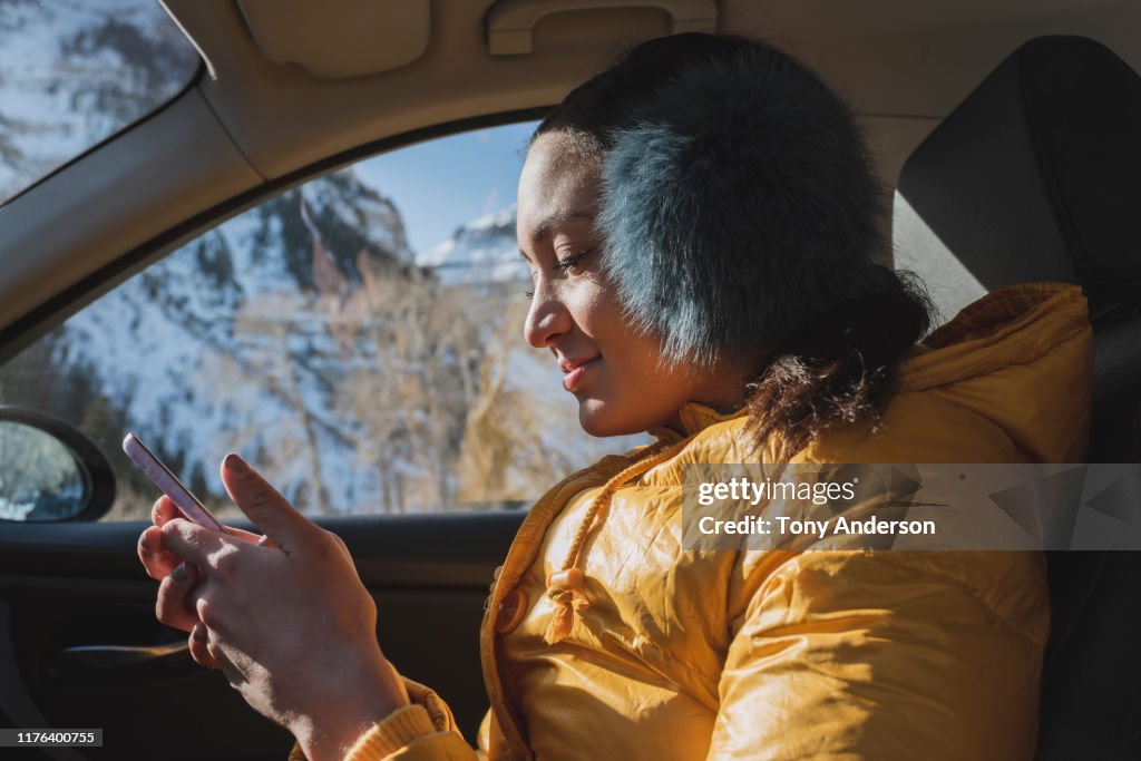 Young woman in car with phone in winter