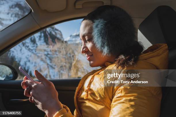 young woman in car with phone in winter - winter yellow nature stock pictures, royalty-free photos & images