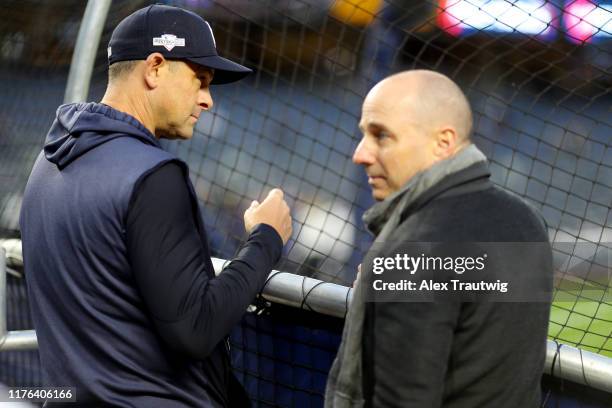 Manager Aaron Boone of the New York Yankees watches batting practice as General Manager Brian Cashman looks on prior to Game 4 of the ALCS between...