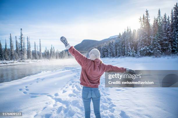 femme en hiver restant près des bras de fleuve s'ouvrent appréciant la liberté et la fraîcheur - les-bras-écartés photos et images de collection