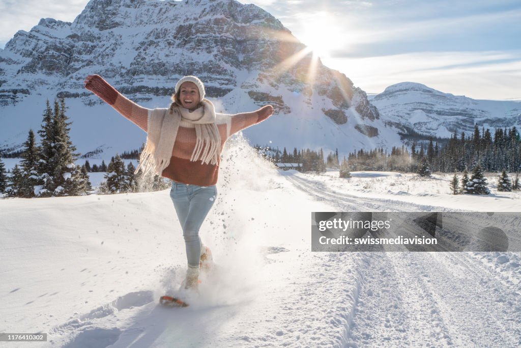 Girl snowshoeing in snowy mountains at sunset having fun and enjoying winter vacations