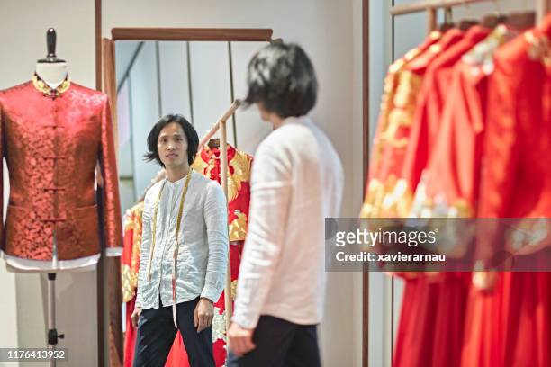 reflection of male chinese wedding dress designer in studio - full length mirror stock pictures, royalty-free photos & images