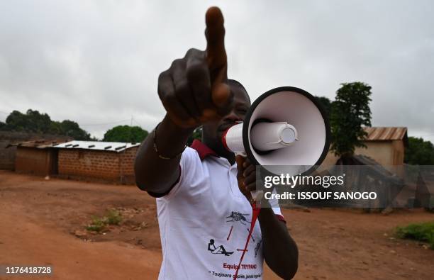 Community health worker calls the villagers with a megaphone so that they can get tested for Human African Trypanosomiasis, also known as sleeping...