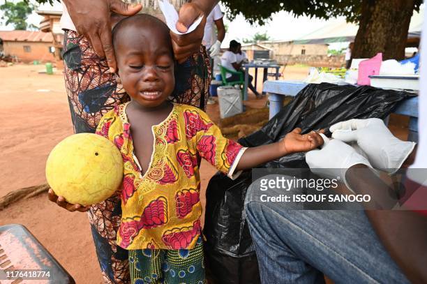Child cries as a healthworker pricks his finger to draw blood as he takes part in an Human African Trypanosomiasis, also known as sleeping sickness,...