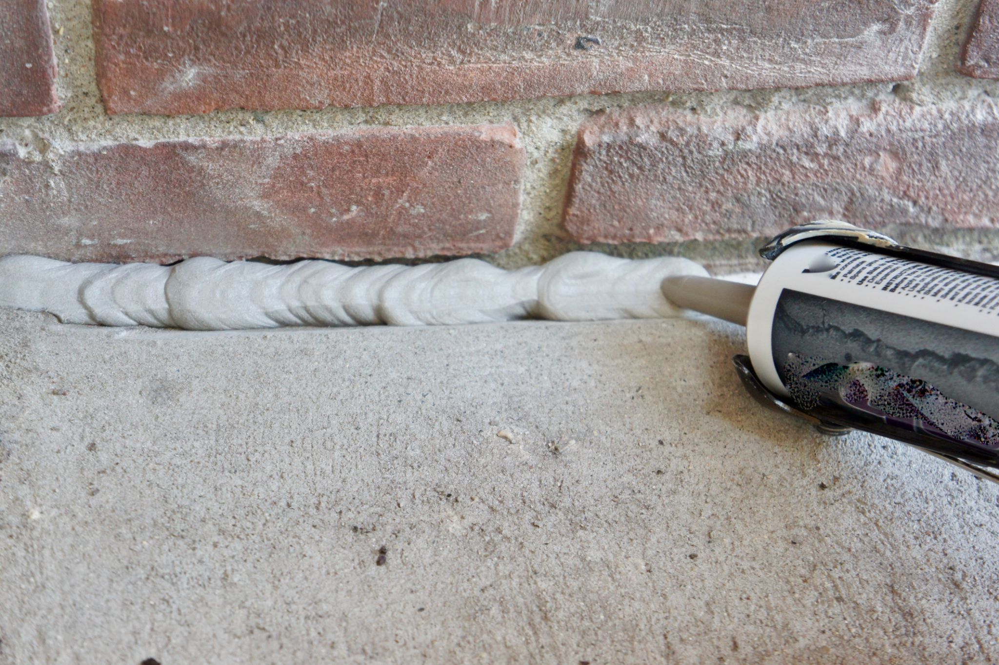 Caulking Concrete by Brick Close-up Caulking Concrete by Brick Close-up