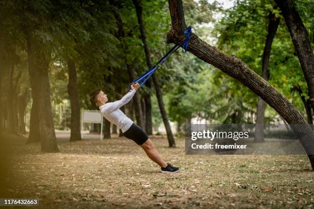 young man workout on suspension straps outdoors - suspension training stock pictures, royalty-free photos & images