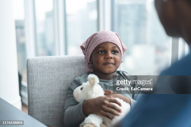 little boy sitting across from his doctor while she comforts him - childhood cancer stock pictures, royalty-free photos & images
