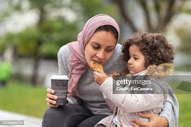 woman with daughter in a city park - muslim girl eating stock pictures, royalty-free photos & images