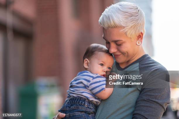 padre de género no binario con bebé - adoption fotografías e imágenes de stock
