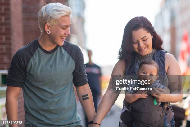jeunes couples heureux marchant avec le bébé - transgenre photos et images de collection