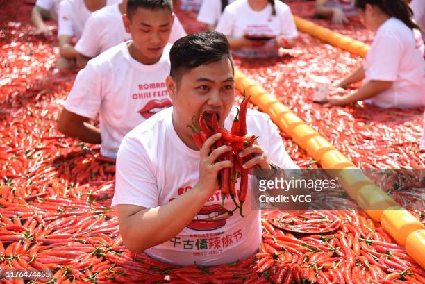 Tourists, sitting in a chili-covered pool, participate in a chili pepper eating contest at Song Dynasty Town on September 22, 2019 in Hangzhou,...