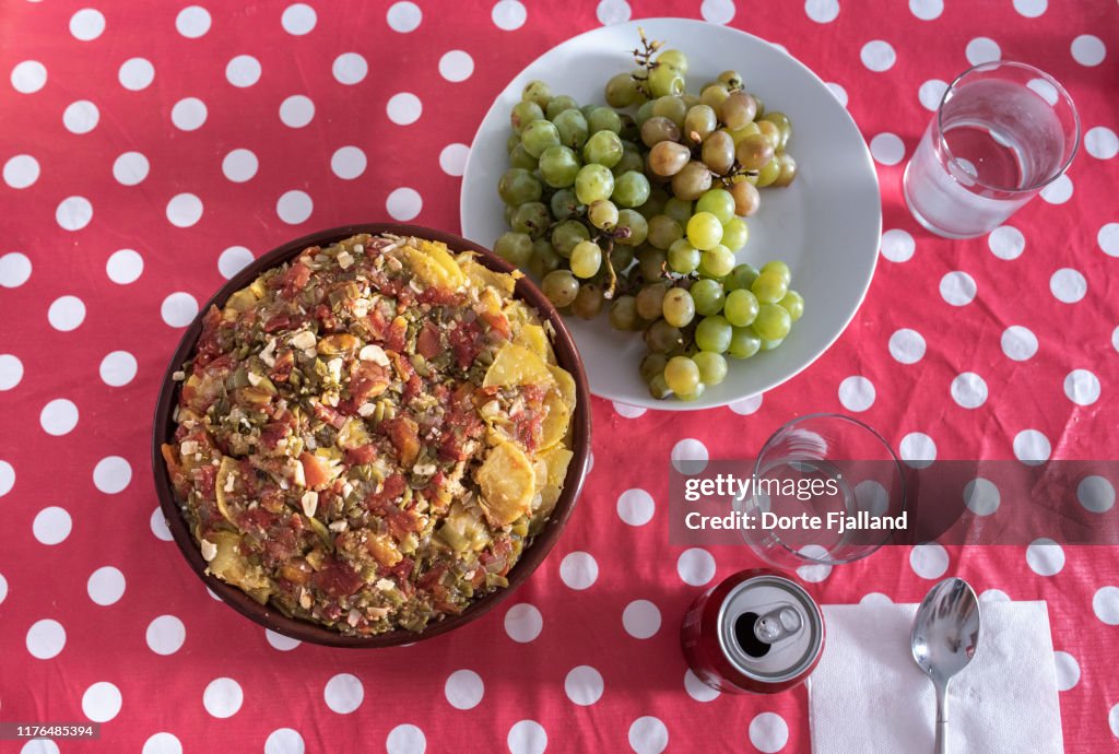 Local dish of bread and potations with fresh moscatel grapes set on a red tablecloth with white dots