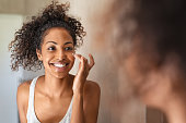 Young black woman applying skin cream