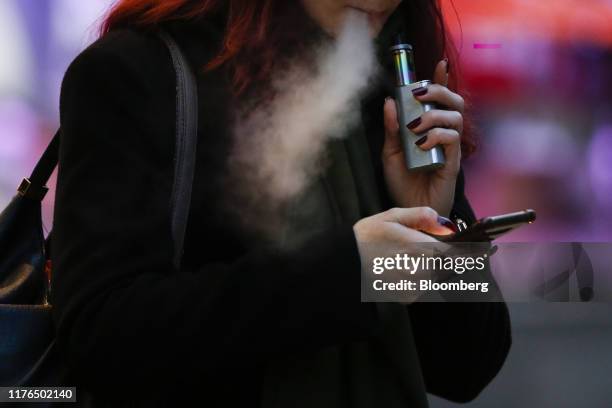 Pedestrian looks at a mobile device while exhaling a cloud of vapour from a vape device in London, U.K., on Thursday, Oct. 17, 2019. Vaping has...