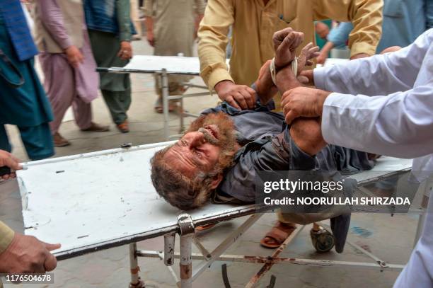 Volunteers carry an injured man on a stretcher to a hospital, following a bomb blast in Haska Mina district of Nangarhar Province on October 18,...