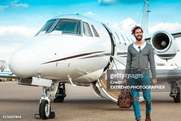 successful man walking away from a private airplane parked on an airport taxiway - billionaires stock pictures, royalty-free photos & images