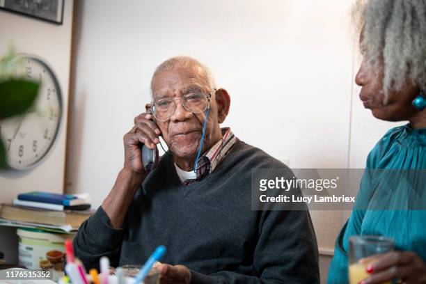 91 year old man talking on the phone, while his daughter is listening - 63 year old female stock-fotos und bilder