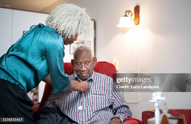 62 year old daughter helping her 91 year old father with his shirt - 90 year old stockfoto's en -beelden