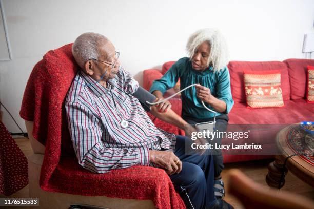 62 year old woman measuring her 91 year old father's blood pressure - 63 year old female stock-fotos und bilder