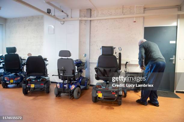 91 year old man getting ready to ride his mobility scooter indoors - 90 year old stockfoto's en -beelden