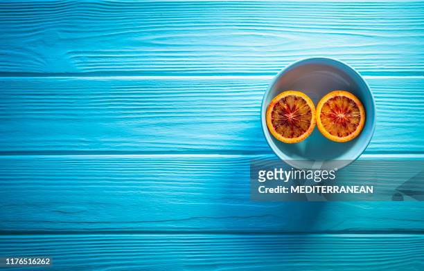 blutorange split in zwei schnitt auf hellblau - blue wooden table stock-fotos und bilder