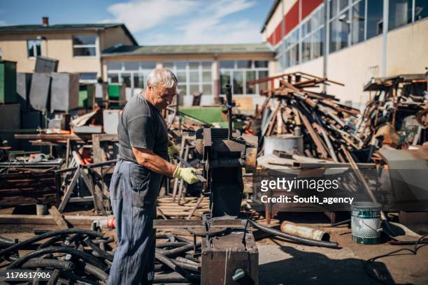 manual worker working in junkyard outdoors - junkyard stock pictures, royalty-free photos & images