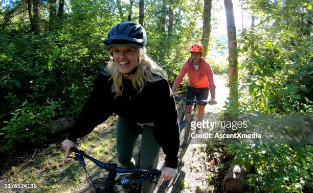 couple mountain bike through forest at sunrise - cycling helmet stock pictures, royalty-free photos & images