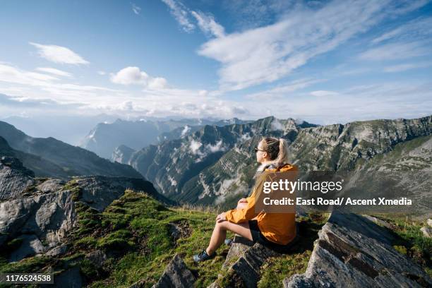 hiker looks off from summit ridge crest, sunshine - orange coat foto e immagini stock