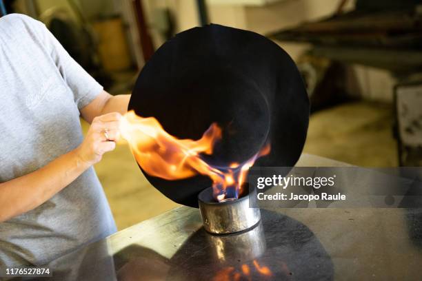 The Borsalino artisan passes the hat on a vertical flame to remove the superficial hair on June 26, 2019 in Spinetta Marengo, Italy.