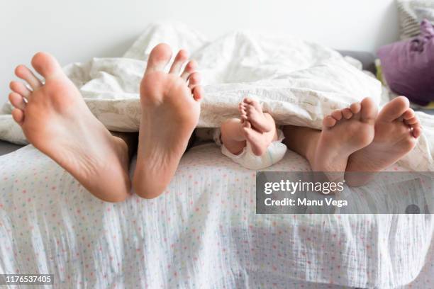 baby you support your feet while walking on your mother lying in bed - wensen stockfoto's en -beelden