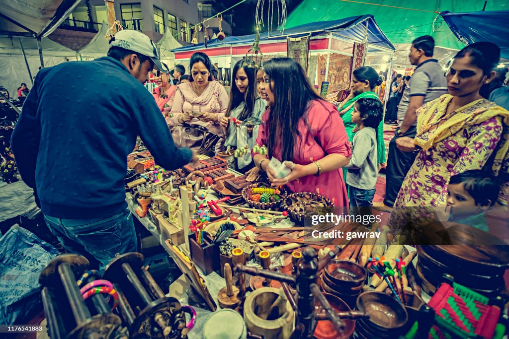Les femmes achètent sur le stand d'objets utilitaires en bois de la foire Himachal Utsav.