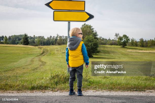 links of rechts, kleine jongen op zoek naar richting in een prachtig groen plateau - cross road children stockfoto's en -beelden