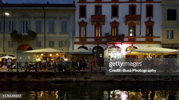 naviglio grande riverfront bustling with people at twilight. milan, italy - milano navigli stock-fotos und bilder
