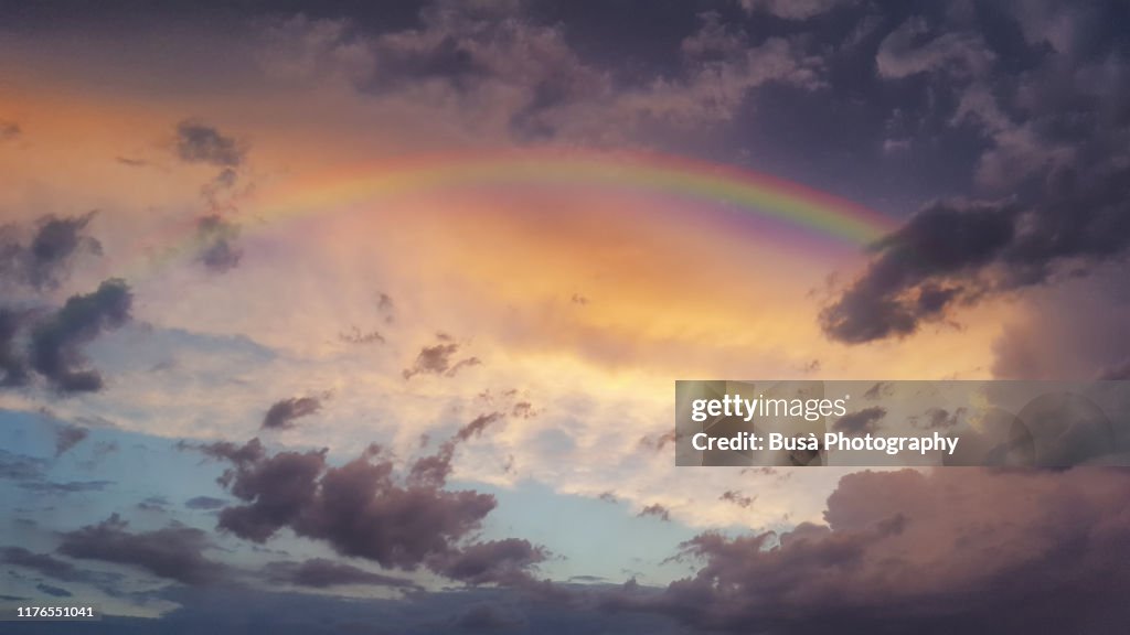 Storm clouds and rainbow at sunset