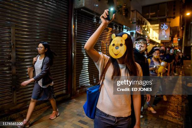 Protester wearing a 'Winnie-the-Pooh' mask joins others to form a human chain along a street in Hong Kong on October 18, 2019. - Hong Kong has been...