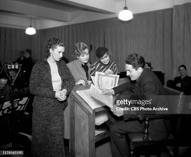 Fred Waring, conductor and band leader gets ready for a CBS Radio broadcast. From left are Rosemary Lane, Priscilla Lane, Babs Ryan and Fred Waring....