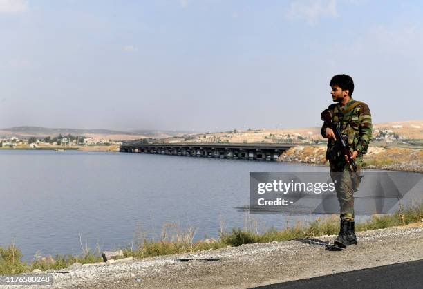 Syrian government soldier walks along the bank of the Euphrates river near the Qarah Qozak bridge in the north of Aleppo governorate near the border...