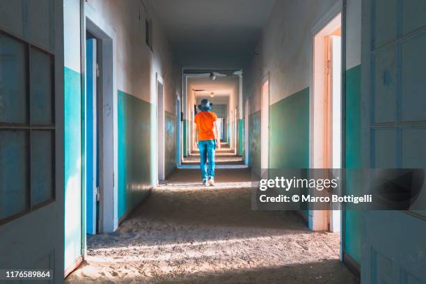 man walking in a corridor of an abandoned building - kolmanskop namibia photos et images de collection