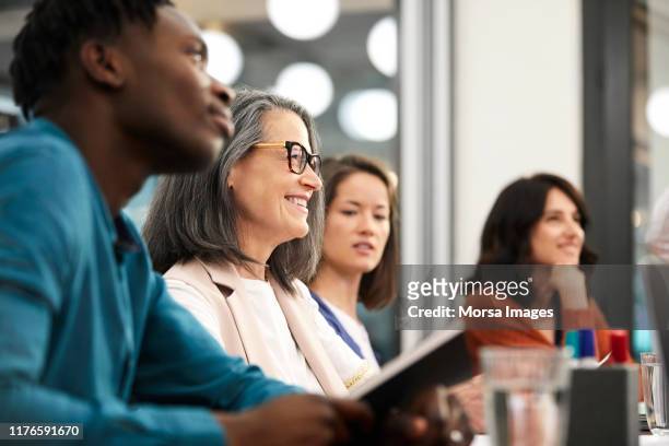 smiling businesswoman looking away with colleagues - board room stock-fotos und bilder