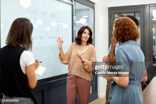 businesswoman explaining plan to colleagues - woman whiteboard stock-fotos und bilder