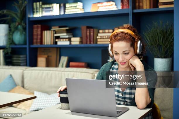 businesswoman using laptop at cafeteria - frau kopfhörer indoor stock-fotos und bilder