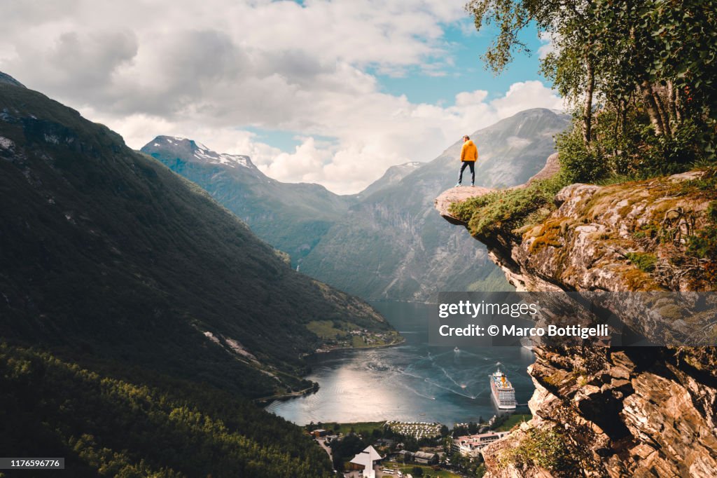 One person standing on top of a cliff over Geiranger, Norway